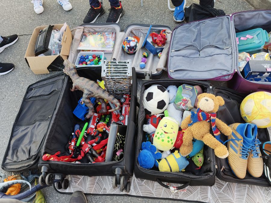 Spielzeug, Plueschtiere und Pokemon-Karten in geoeffneten Koffern als Flohmarkt-Angebot