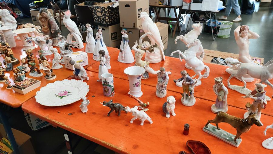 Große Sammlung Porzellanfiguren: Hummelfiguren, ein aufbäumendes Pferd, Tanzfiguren, Vögel und Tierfiguren auf einem Flohmarkttisch.