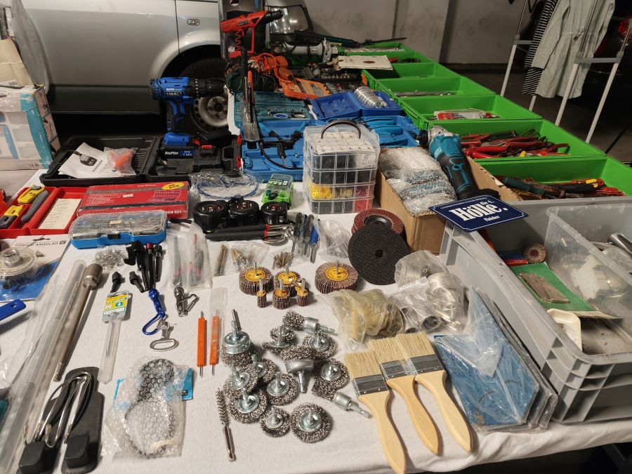 Werkzeugstand mit Akkuschrauber, Zangen, Drahtbürsten und Werkzeugkisten auf einem Flohmarkt.