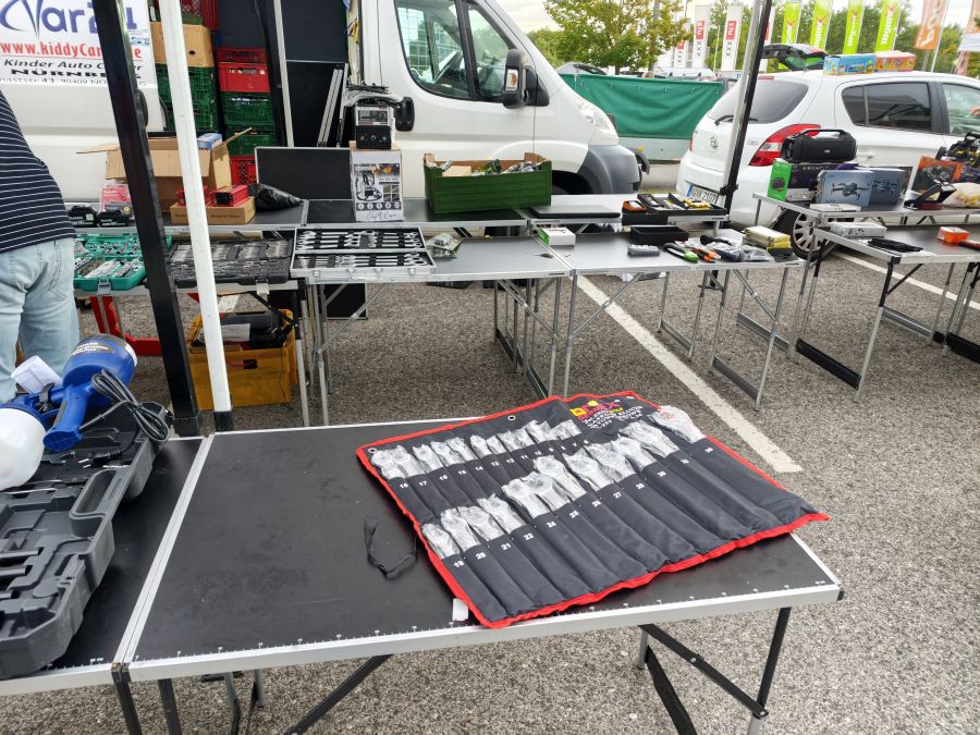 Werkzeug- und Elektronik-Neuwarenstand mit Ratschenschlüssel-Set, Schweißgerät und Mini-Drohnen auf einem Flohmarkt.
