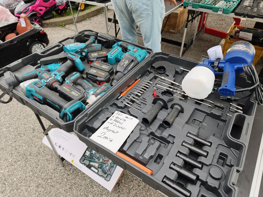 Werkzeugkoffer mit Boxer-Akkuwerkzeugen, Akkus und Farbsprühsystem auf einem Flohmarkt.