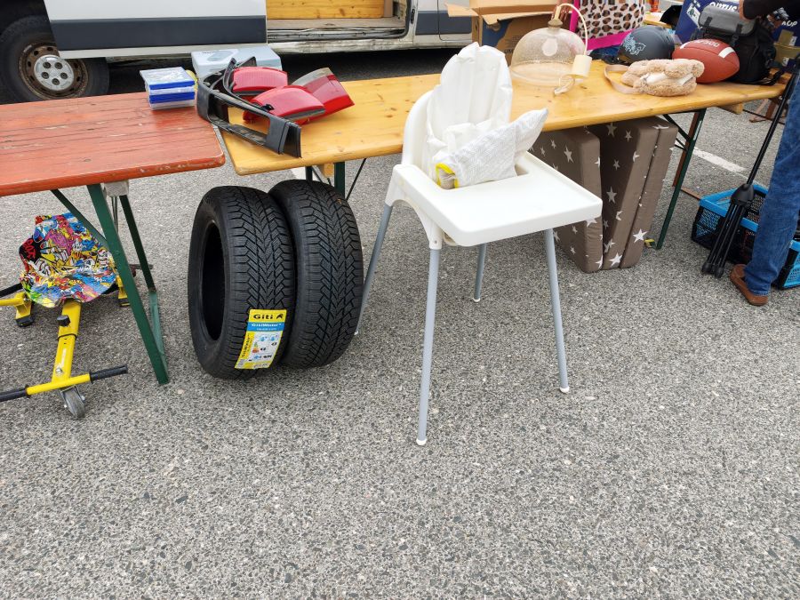 Zwei neue Giti-Winterreifen neben einem Kinderhochstuhl und Kfz-Rücklichtern auf einem Flohmarkt.