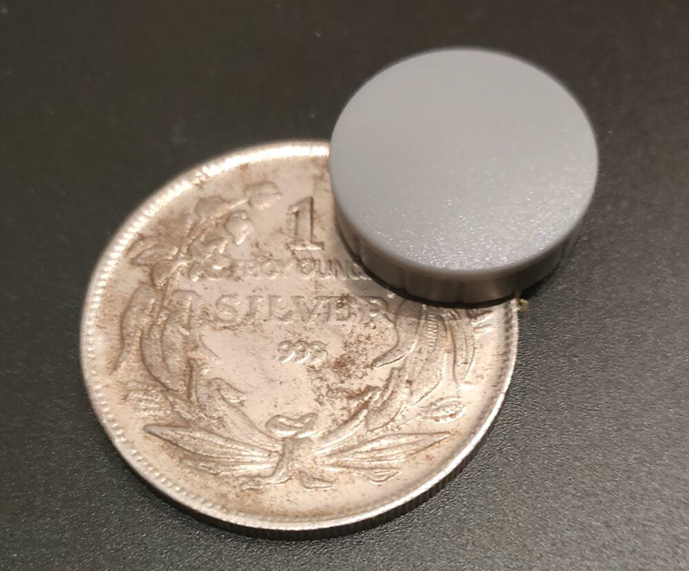 Ein Magnet bleibt an einer als '1 Troy Ounce Silver .999' geprägten Münze haften – ein deutliches Zeichen, dass es sich nicht um echtes Silber handelt